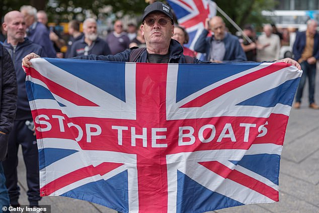 A man protesting immigration holds a sign reading 'stop the boats' outside the New Bridge Hotel in Newcastle on August 23