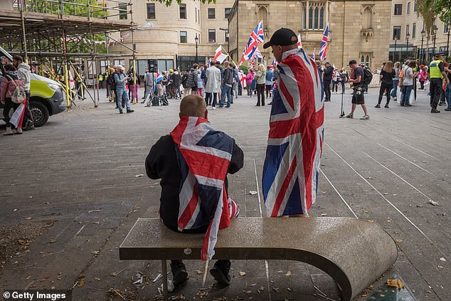 Two men draped in Union Jack flags sit on a bench during an anti-immigration protest in Newcastle
