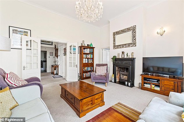 Her new apartment's large living room boasts a spacious living area and a small chandelier