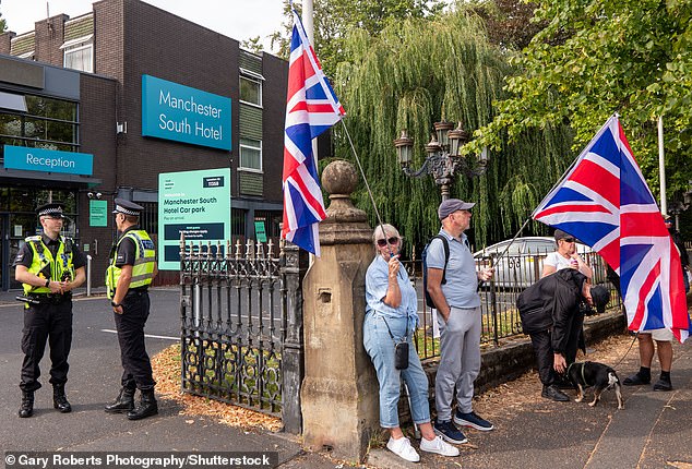 Crowds wave flags outside the hotel in Manchester as police officers watch on