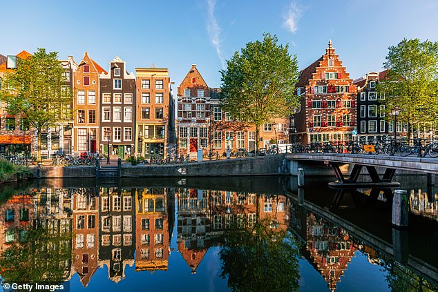 Four-day weeks are becoming 'very common' among Dutch workers, says an economist. Pictured: Historic Dutch houses reflecting in the canal on a sunny day, Amsterdam, Netherlands