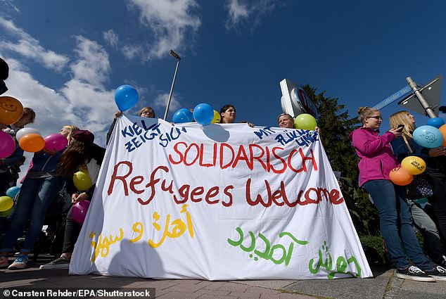 Germany has had a 'seine Meinung andern' – a change of mind – after letting in so many migrants (pictured: residents welcoming a bus of refugees in Kiel in 2015)