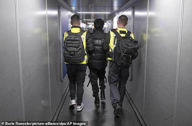 Officers from the Federal Police pictured taking a man on a deportation flight to Pakistan. Germany has turned its back on mass immigration as the economy falters and crime soars