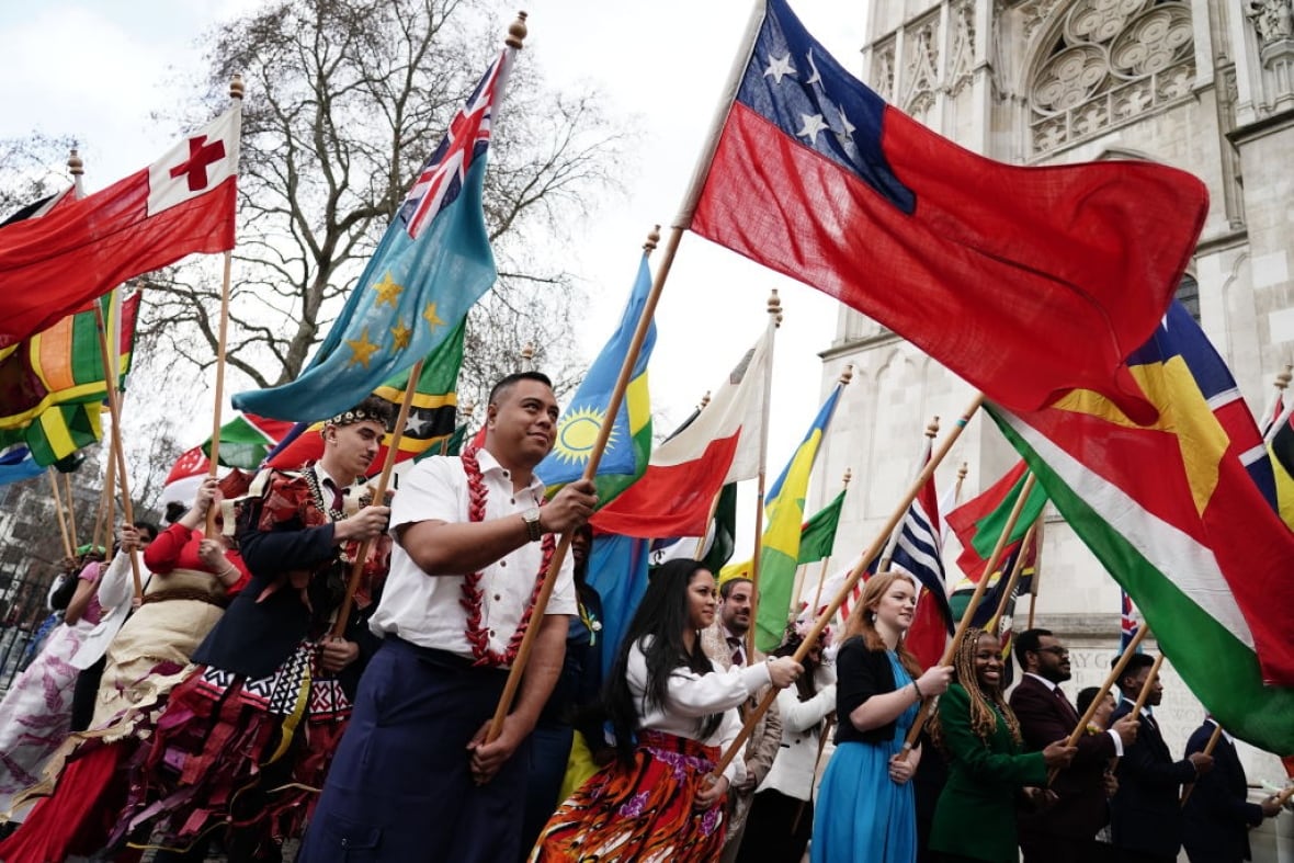 Several people parade flags in front of a large abbey.