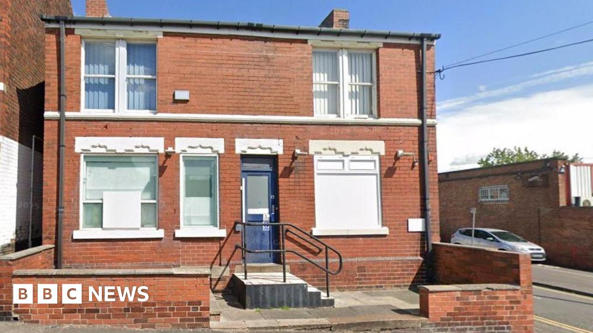 A two-storey end-of-terrace building, with a blue door and small set of steps leading to the threshold.