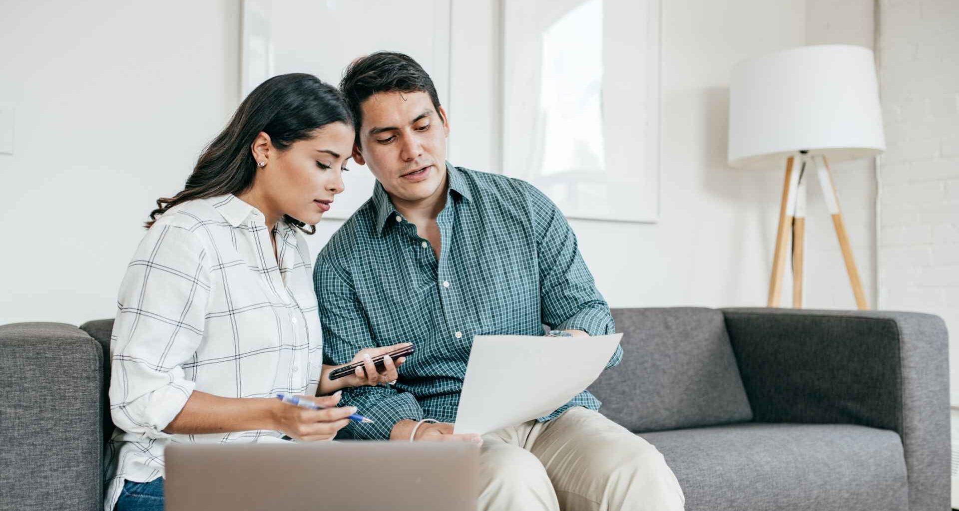 Couple sitting on a couch and looking at bank statements.