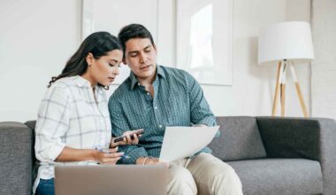 Couple sitting on a couch and looking at bank statements.