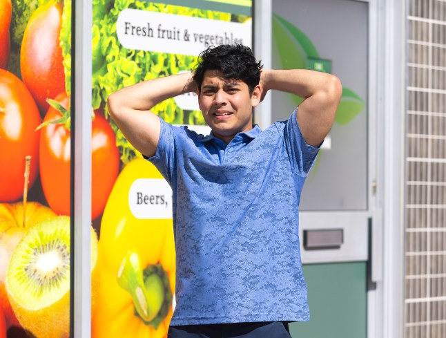 Aadi looks horrified while standing outside the shop in Corrie