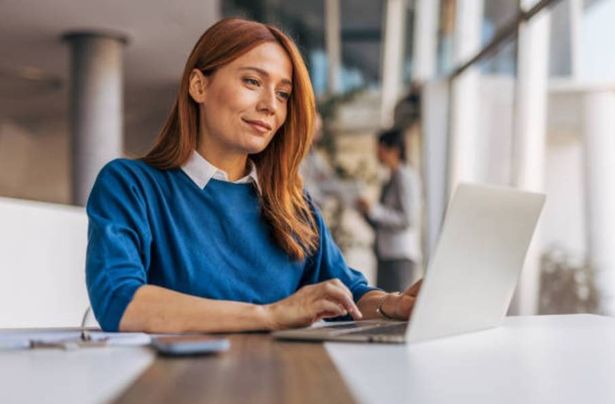 Young woman working at a desktop using laptop