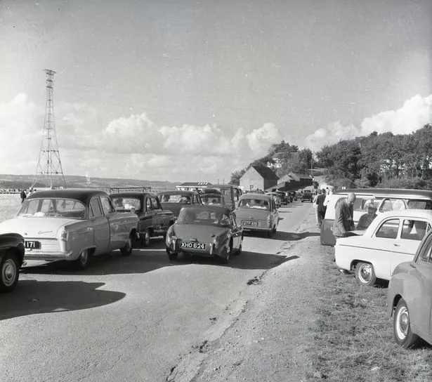 A black and white photo of cars in 1960 waiting for a ferry