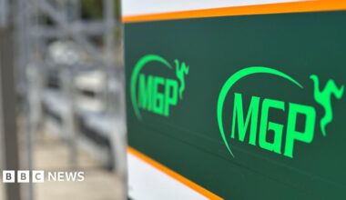 A sign in the pitlane at the grandstand featuring the MGP logo, which includes a semi-circle with a three legs of Mann emblem at one end.