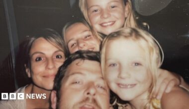 A family photo of the Bastion-Strong family showing Chris and Katie with their three daughters. The family are all close together and smiling as they pose for the picture.