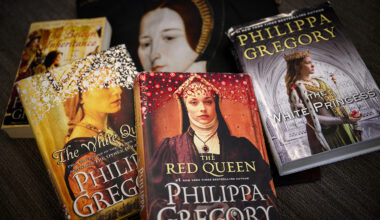 A collection of five Philippa Gregory historical fiction novels displayed on a dark surface. The books shown are 'The White Queen,' 'The Red Queen,' and 'The White Princess,' all part of The Cousins' War series. The book covers feature portraits of women in medieval and Tudor-era clothing and headdresses, with rich colors including gold, red, and purple. The author's name 'PHILIPPA GREGORY' is prominently displayed on each cover.
