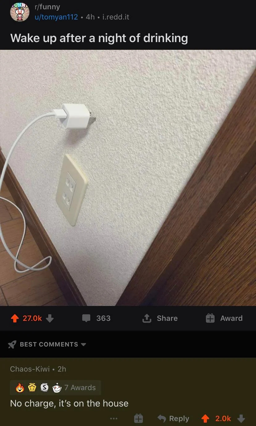 Power outlet and phone charger cord attached to a wall, resting on the floor