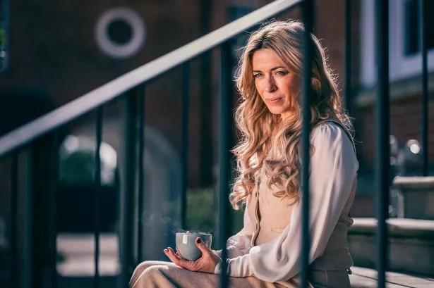 Eve Myles drinking a coffee on the stairs