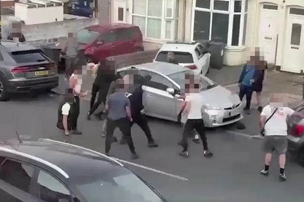 Video grab from terrifying footage shows a machete wielding thugtrying to stab two men after a huge 'Wild West-style' mass brawl erupted on a residential street involving up to 20 people.