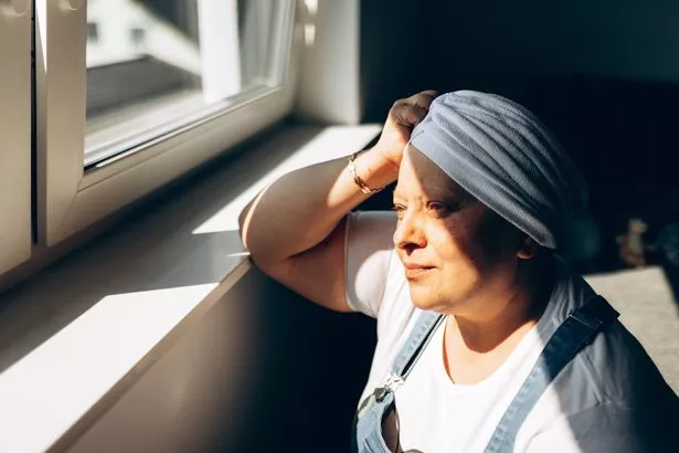 Stock image of a woman, wearing a head covering, recovering from chemotherapy in hospital.