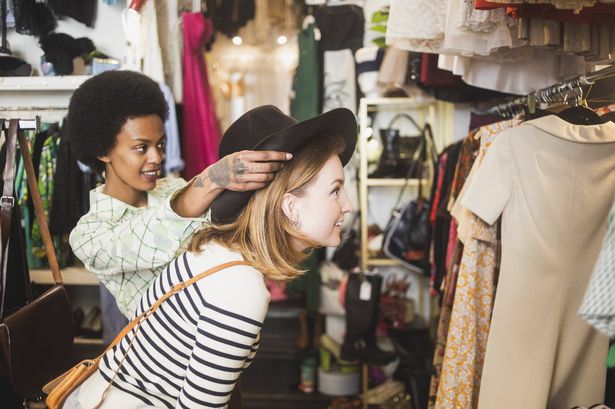 Stock image of a charity shop worker helping a female customer buy items