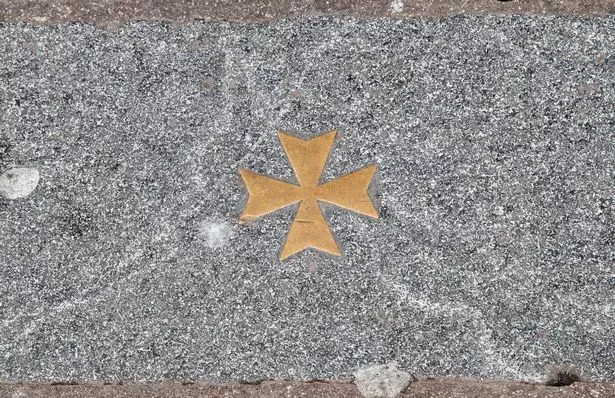 A tiny brass Maltese cross