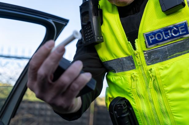 A UK police officer holding a breathalyser