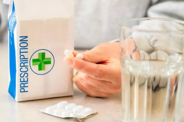 Close-up of two pills held, ready for taking by a woman from a prescription bag..