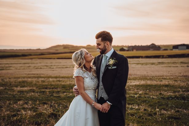 A couple looking at each other at sunset in their wedding outfits