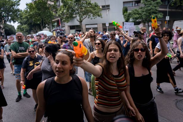 BARCELONA, SPAIN - 2025/06/15: People are seen spraying tourists and buildings with water guns and pistols during the demonstration. With more than 20 million tourists expected in 2025, there is increasing contempt toward mass tourism among local citizens due to rising housing prices and overcrowding of the city during the tourist season. (Photo by Davide Bonaldo/SOPA Images/LightRocket via Getty Images)