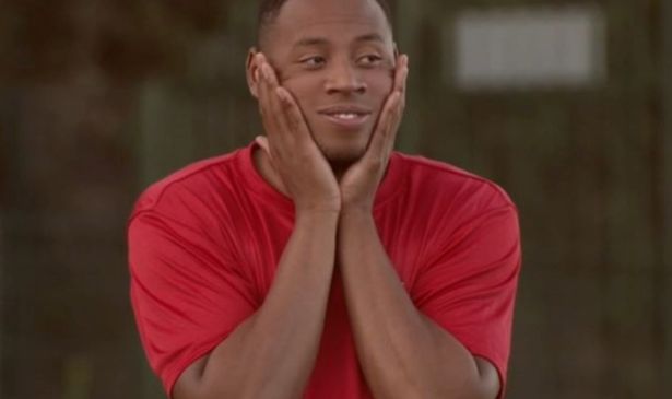 A man in a red top with his hands either side of his face looking stressed