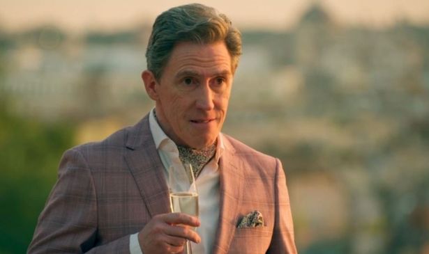A man in a pink suit holding a glass of champagne 