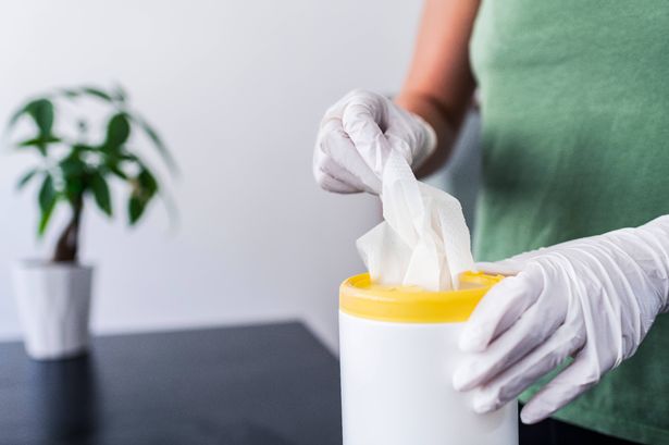 Stock image of a woman cleaning table using disinfectant wipes. Health concept image.