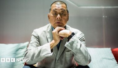 Jimmy Lai, in a gray suit and black pants, poses for a photograph during an interview with AFP news agency in Hong Kong