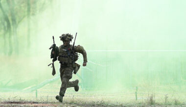 An Australian soldier from Battle Group Kapyong runs through green smoke during an clearance of enemy positions