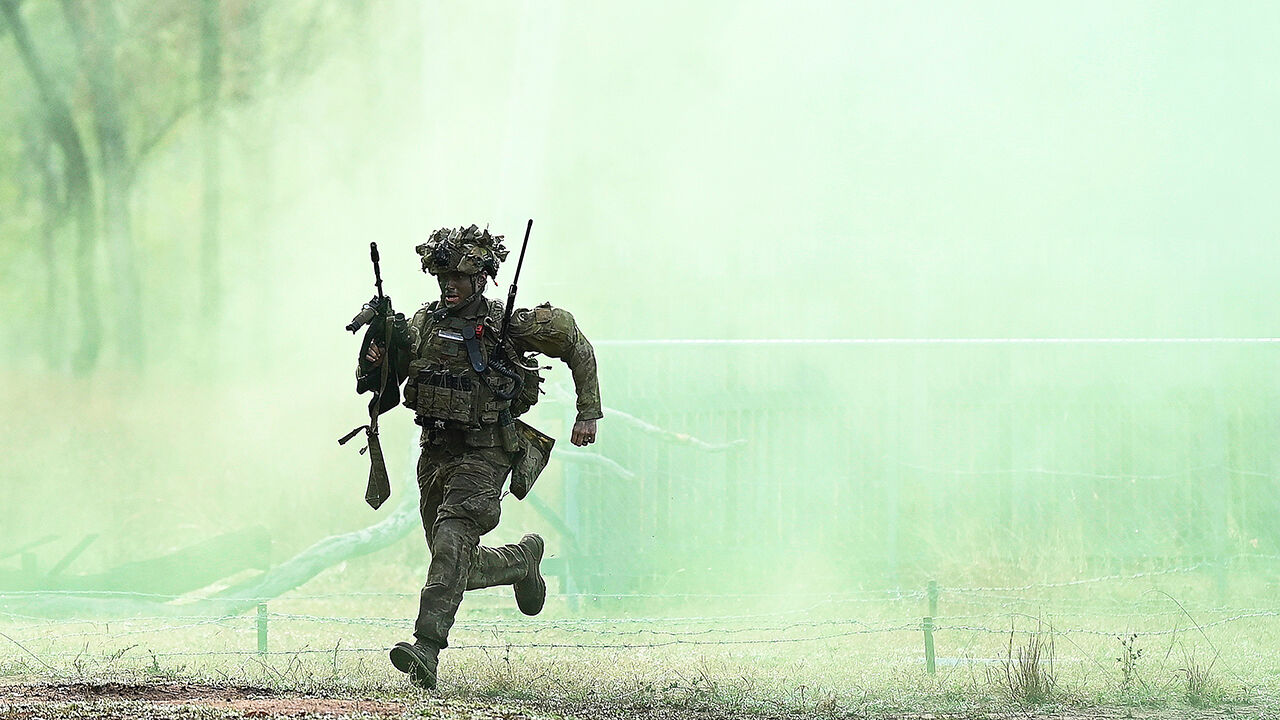 An Australian soldier from Battle Group Kapyong runs through green smoke during an clearance of enemy positions