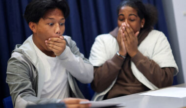 Joshua Boado, 16, and Rahnai Henricus, 16, students at Harris Academy Merton, react as they collect their GCSE results, in London