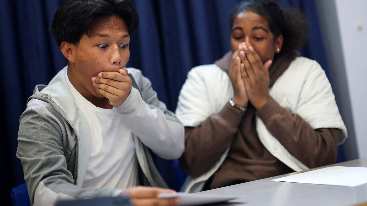 Joshua Boado, 16, and Rahnai Henricus, 16, students at Harris Academy Merton, react as they collect their GCSE results, in London