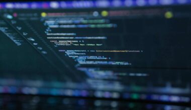 Lines of code on a laptop screen with text highlighted in orange, blue, white, and green on a dark background. Open source