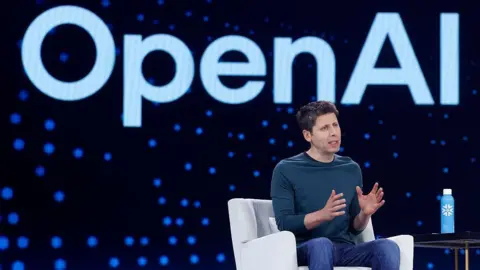 Getty Images  Open AI CEO Sam Altman speaks during Snowflake Summit 2025 at Moscone Center on June 02, 2025 in San Francisco, California. He is seen sitting on a white arm chair, wearing a dark long-sleeved dark teal shirt and blue denim jeans, gesturing with his hands as he speaks towards a crowd (not pictured). Behind him is a large electronic screen displaying the OpenAI logo. 