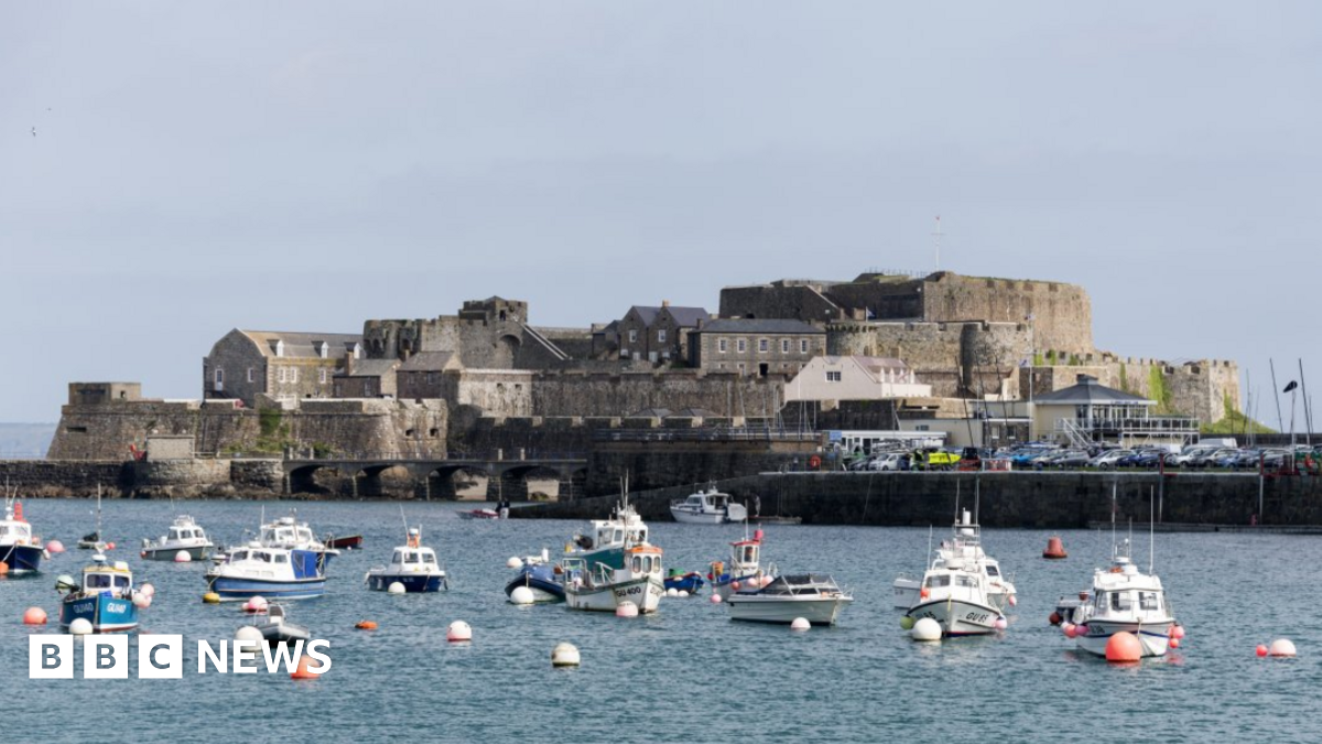 A view of Castle Cornet on an island with a number of small boats on the water in front of it.