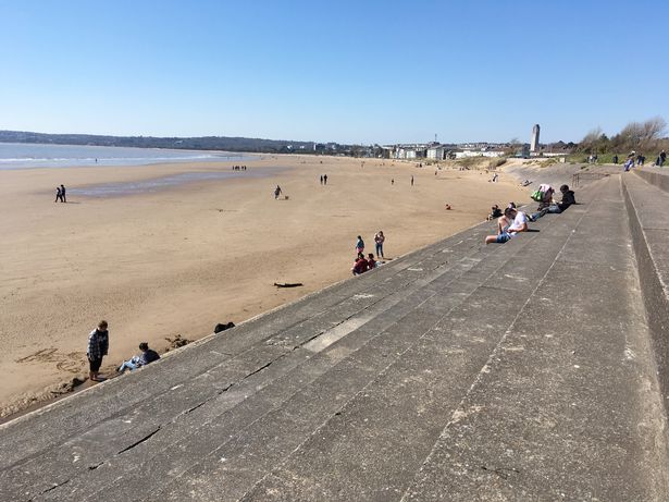 Photo shows people sat on sandy beach