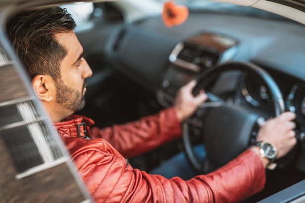 Young handsome man driving luxury car. Successful businessman driving new car to work and back home. Indian man is also using possibility of crowd-sourced taxiing to earn additional money for personal income
