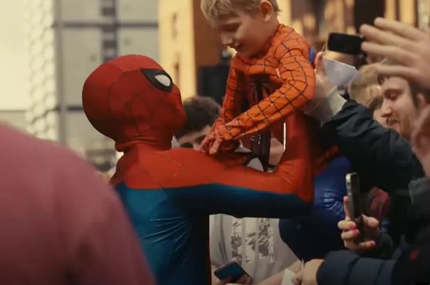 Spider-Man (Tom Holland) lifting Sam over the barrier in Glasgow city centre.