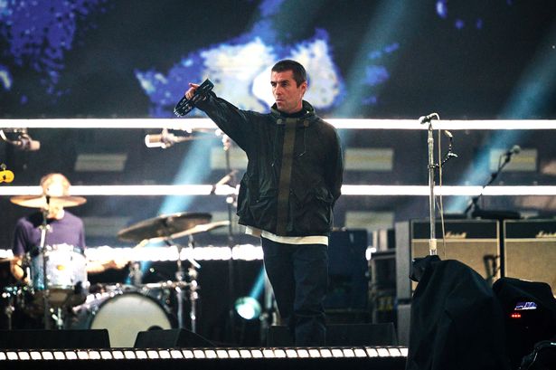 Liam Gallagher of Oasis performs on stage during the opening night of their Live 25' Tour at Principality Stadium on July 04, 2025 in Cardiff, Wales wearing parka and holding tambourine