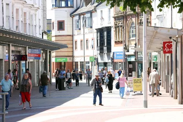 A town centre on a sunny day with people walking around 