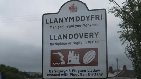 BBC A white road sign in Llandovery with the town's name written in Welsh and English. The sign also has 'The birthplace of rugby in Wales' written on it. 
