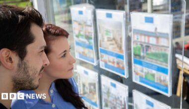 Homebuyers look at an estate agents window display - stock shot