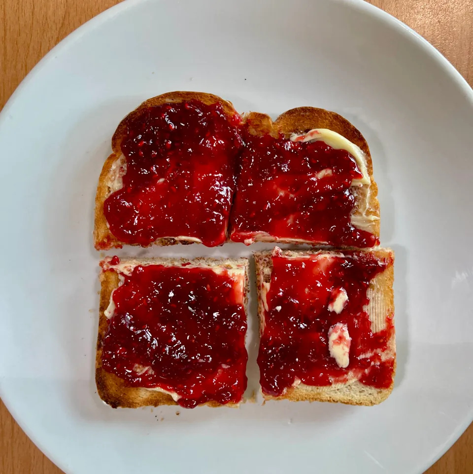 Cut up pieces of toasted bread with strawberry jam on in close up