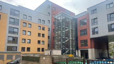 Simon Thake The exterior of a large block of apartments with a large stairwell and windows