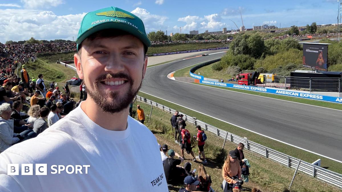 Brandon Burgess smiles while taking a selfie with the Zandvoort circuit in the background