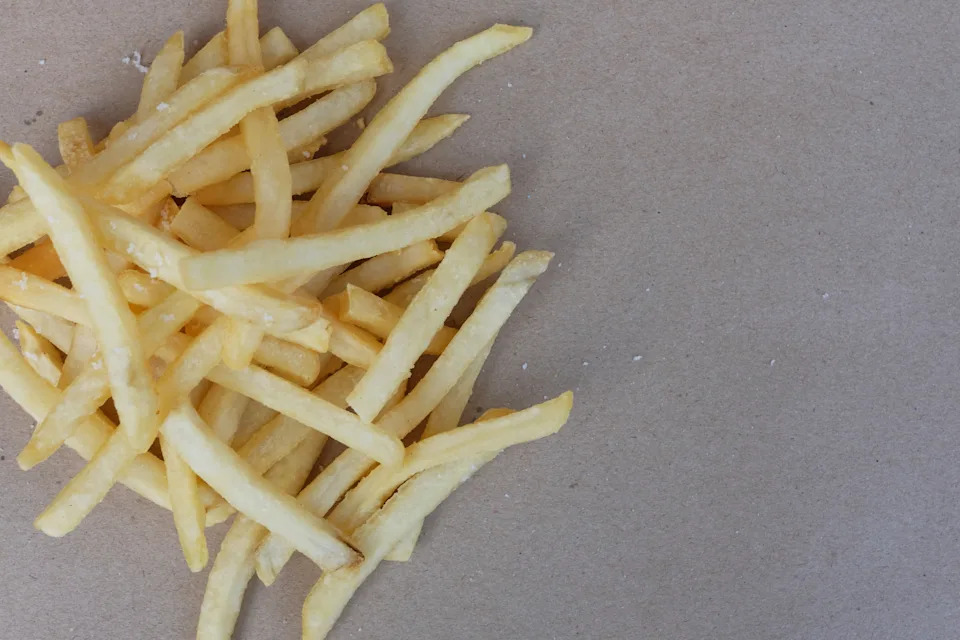 Unhealthy junk food, group of cheesy french fries on brown paper with blank space, copy space, fast food concept