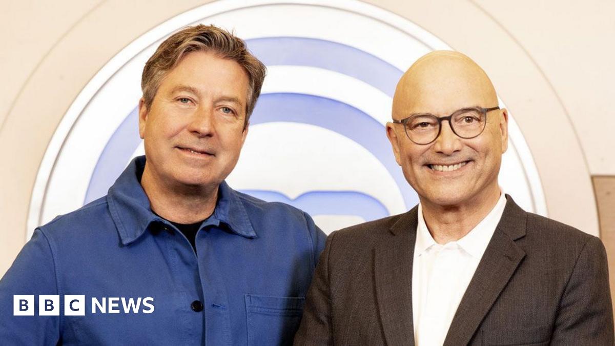 Designed image showing headshots of Gregg Wallace and John Torode. Wallace is on the left, he has a shaved head, black rimmed glasses and is wearing a white open-necked shirt with grey jacket. Torode has short greying hair, a white open-necked shirt and grey jacket.